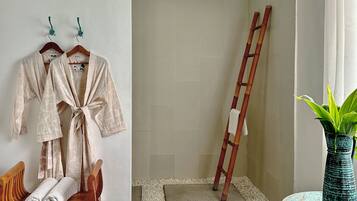 Un baño con un banco de madera, un perchero con batas, una escalera y una planta en maceta.