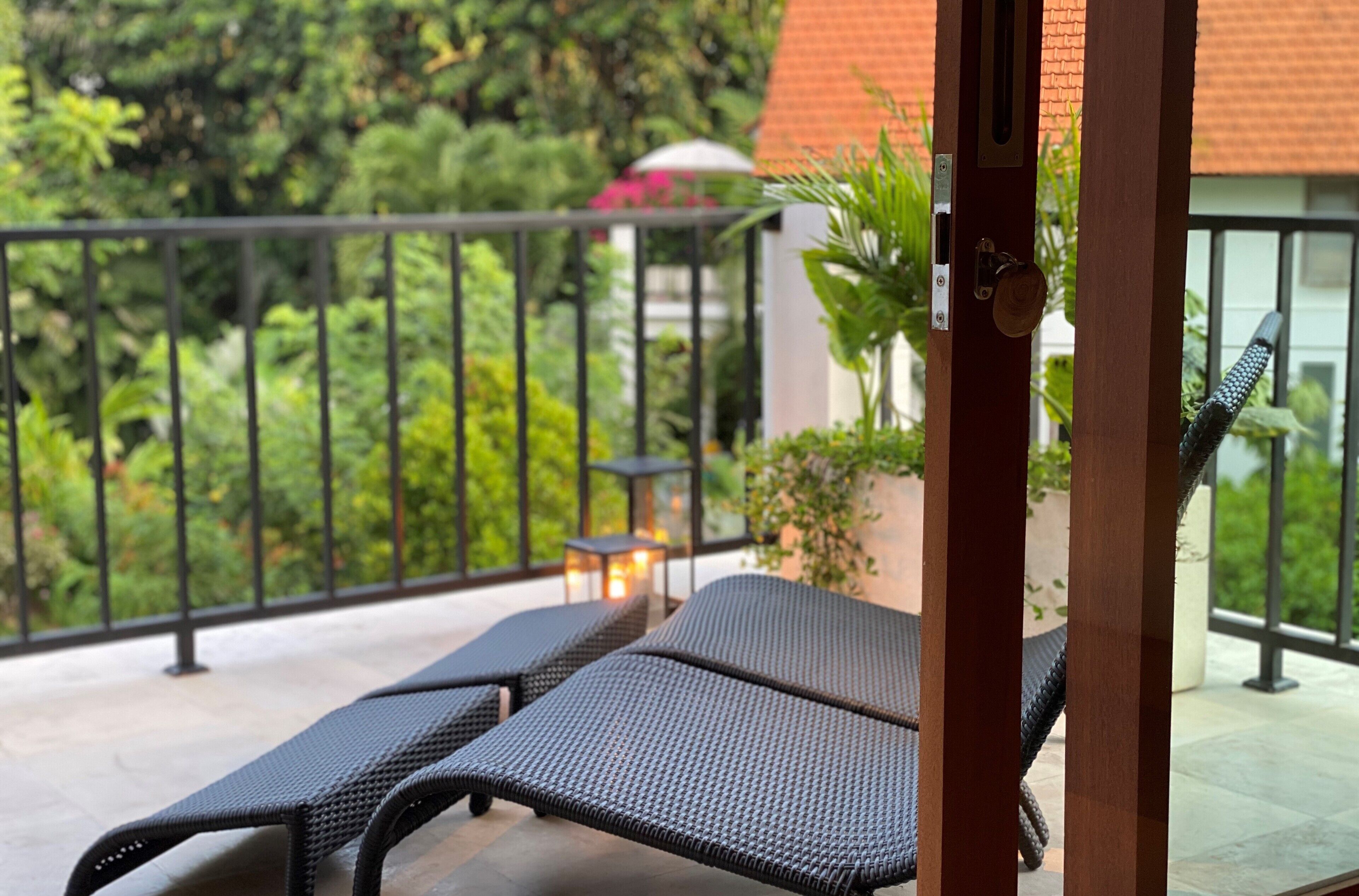 A balcony with two lounge chairs, a small table, and a potted plant.