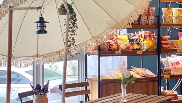 A table with a wooden bench, a hanging lantern, and an umbrella with fringe details. - Stay Pohang Hotel (Pohang)