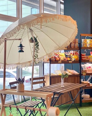 A table with a wooden bench, a hanging lantern, and an umbrella with fringe details. - Stay Pohang Hotel (Pohang)