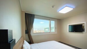 A hotel room with a bed, a television mounted on the wall, a window with curtains, and a ceiling light. - Stay Pohang Hotel (Pohang)