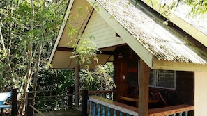 A wooden building with a sloped roof, a porch with a railing, and a sign above the door.