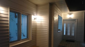 A hallway with wooden steps leading to a door, flanked by windows with blinds. - Agit Guesthouse (Seoul)