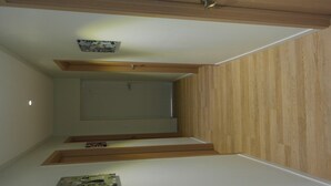 A narrow, wooden-paneled stairway leading to a landing with a door and a small shelf with items. - Agit Guesthouse (Seoul)