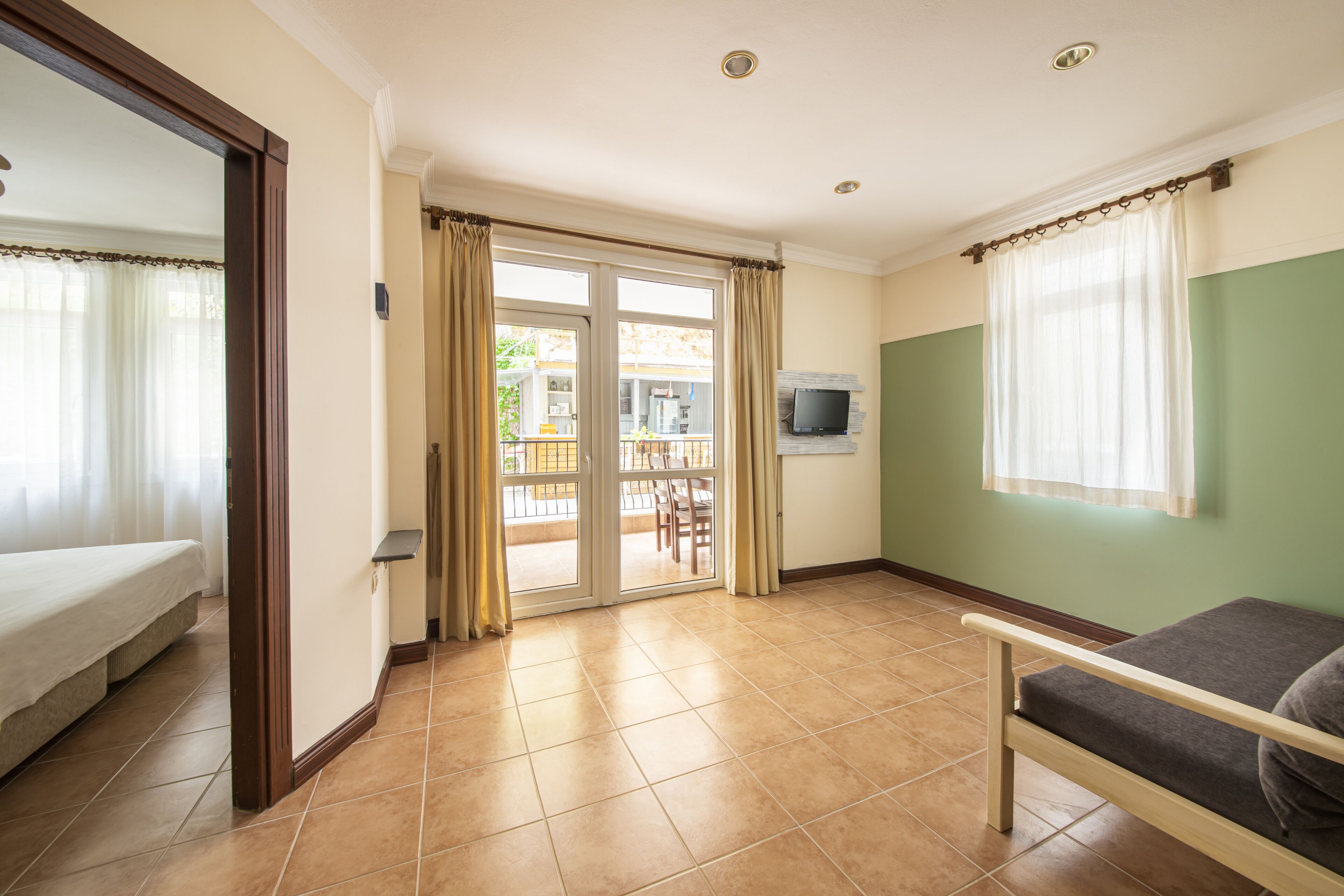Een hotelkamer met een bed, een bank, een televisie en een schuifdeur naar een balkon.
