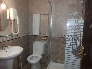 A bathroom with a toilet, sink, and shower.