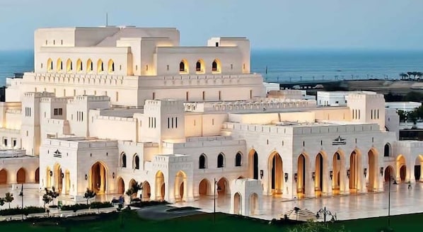 A large, white, multi-story building with numerous arched windows and a central courtyard.