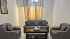 Uma sala de estar moderna com um sofá cinza, uma mesa de centro de madeira e um candelabro.