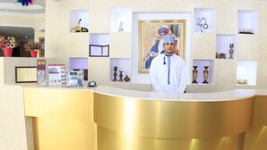 Um balcão de receção de hotel dourado, com certificados emoldurados e objetos decorativos nas prateleiras.