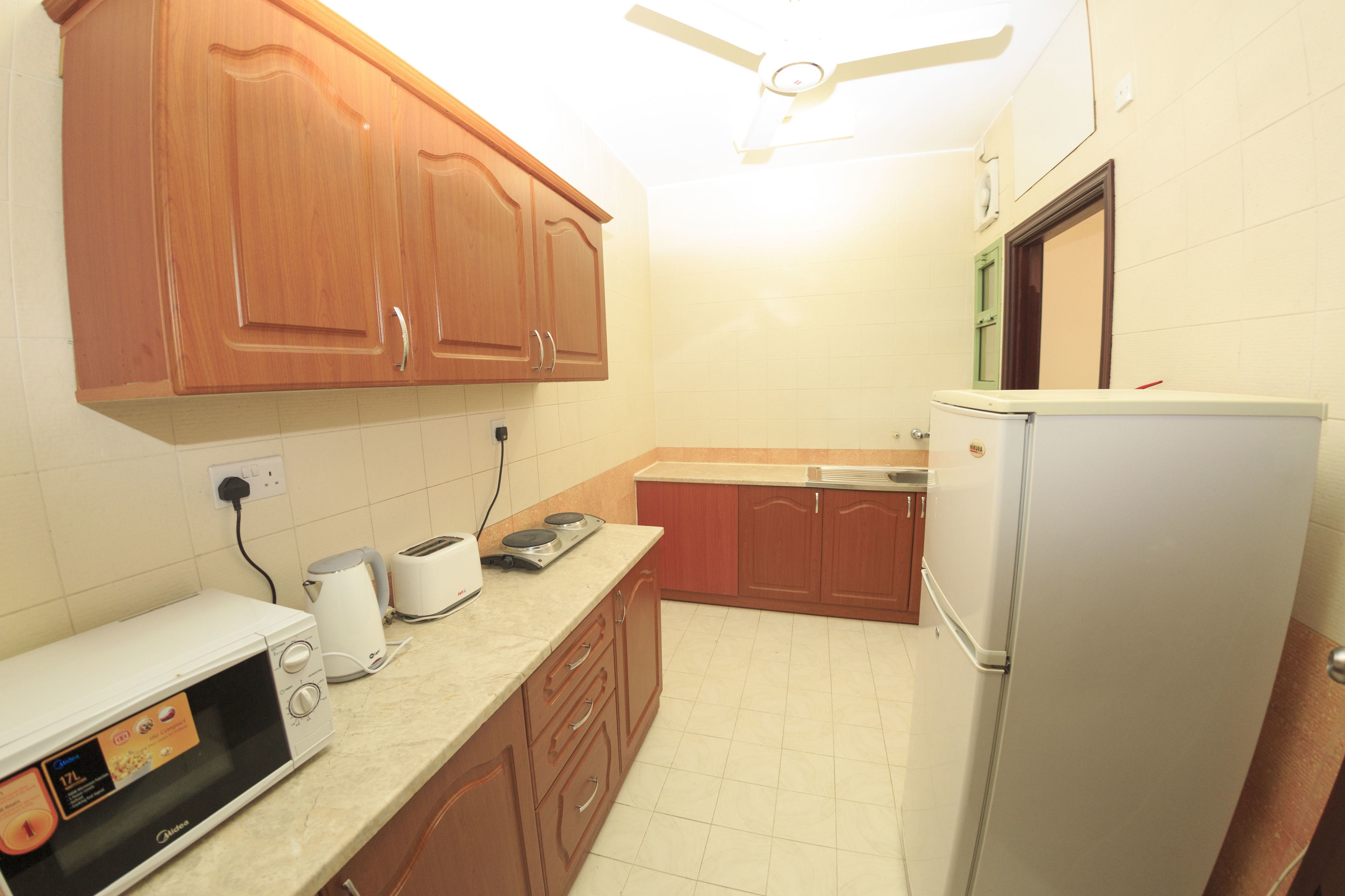 A kitchen with wooden cabinets, a microwave, a toaster, and a refrigerator.