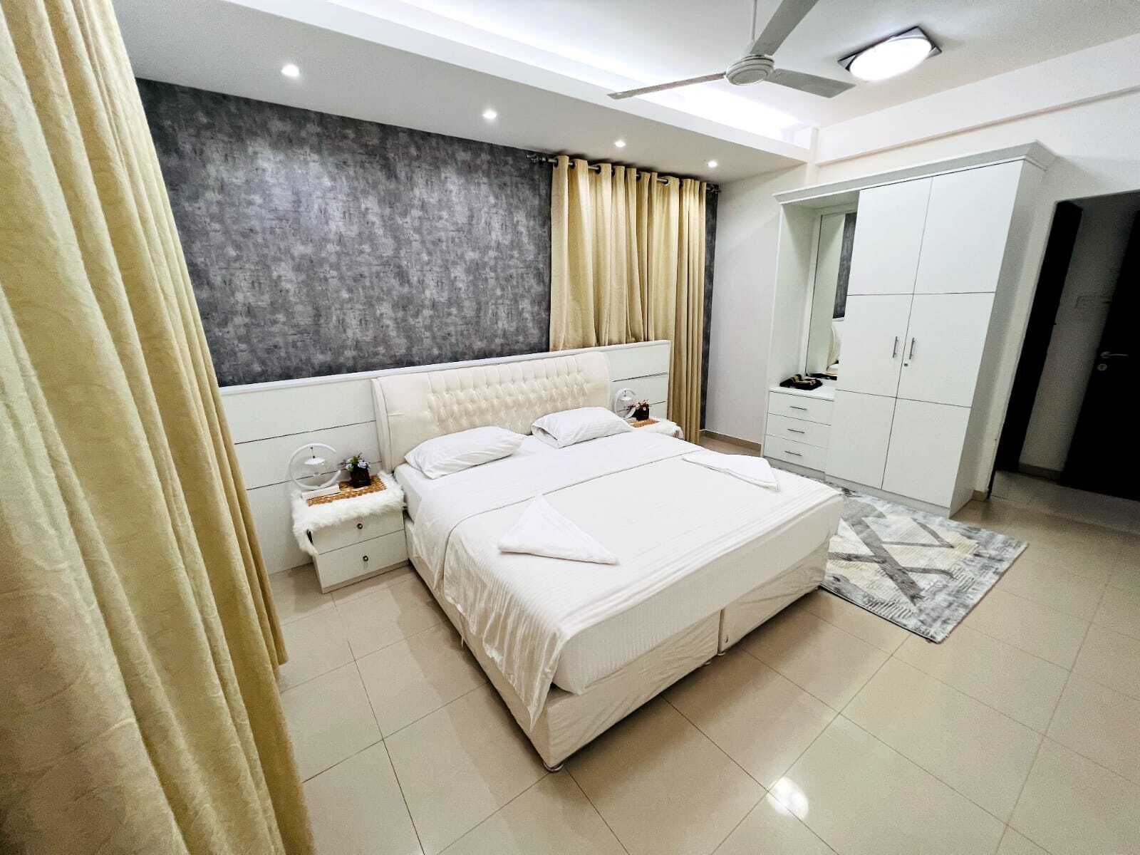 Ein modernes Schlafzimmer mit einem großen Bett, Nachttischen, einem Kleiderschrank und einem Deckenventilator.
