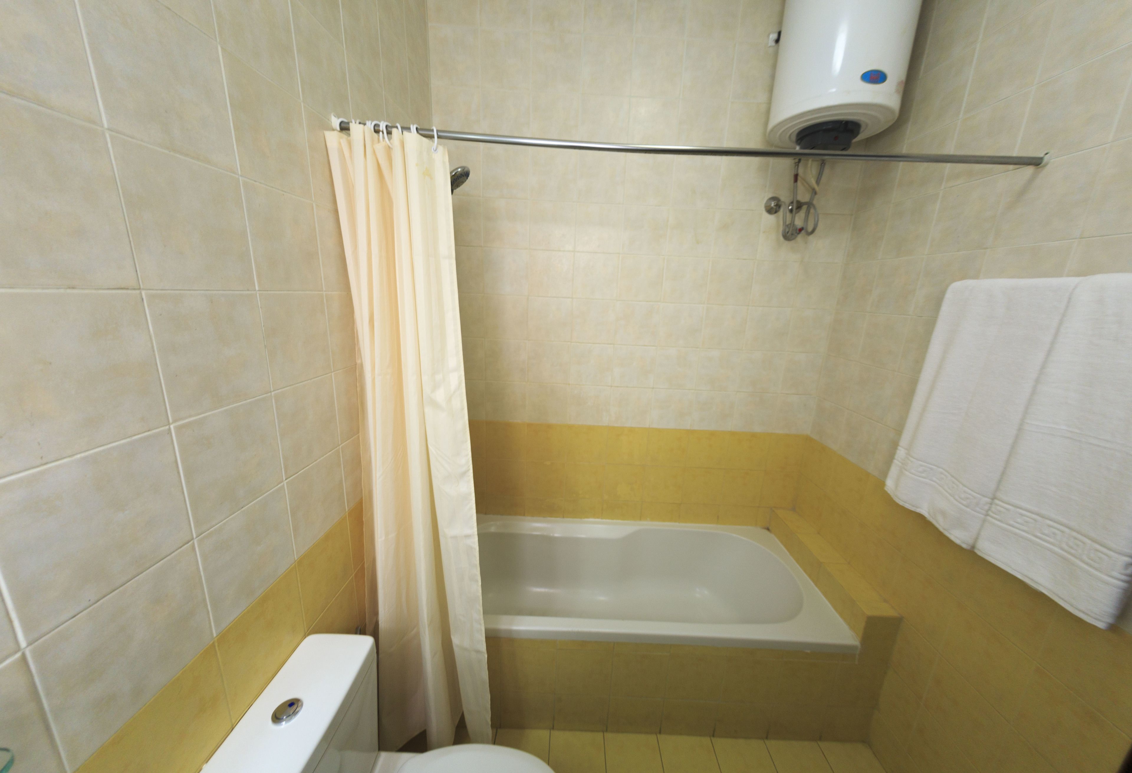 Une salle de bain avec une baignoire, des toilettes et un rideau de douche.