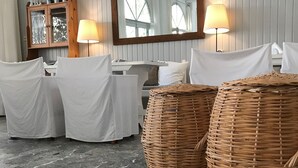 Ein Zimmer mit Marmorboden, zwei Polsterstühle, einem Tisch, einem Spiegel und zwei Korbwannen.