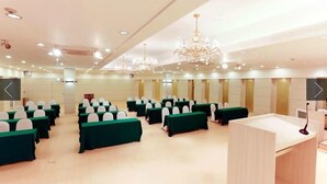 A conference room with rows of tables and chairs, a podium, and chandeliers. - Gimcheon Park Tourist Hotel (Gimcheon)