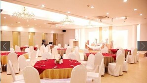 A banquet hall with round tables covered in red tablecloths, white chairs, and chandeliers. - Gimcheon Park Tourist Hotel (Gimcheon)