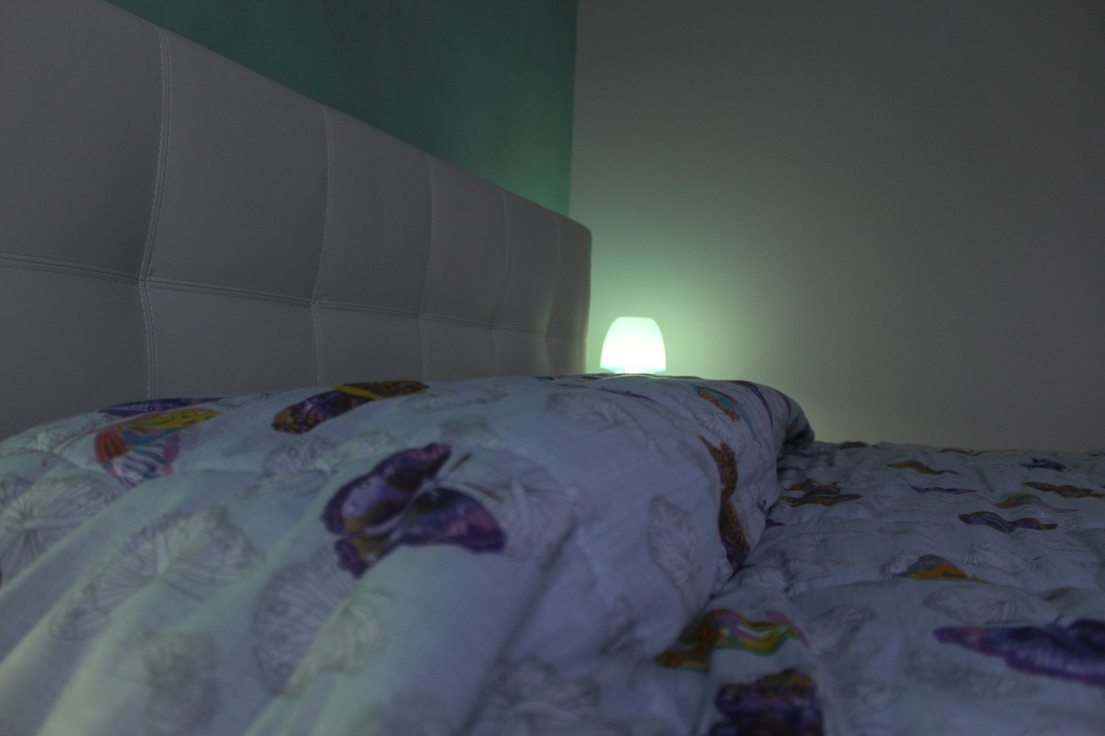 A bed with a patterned blanket and a headboard.
