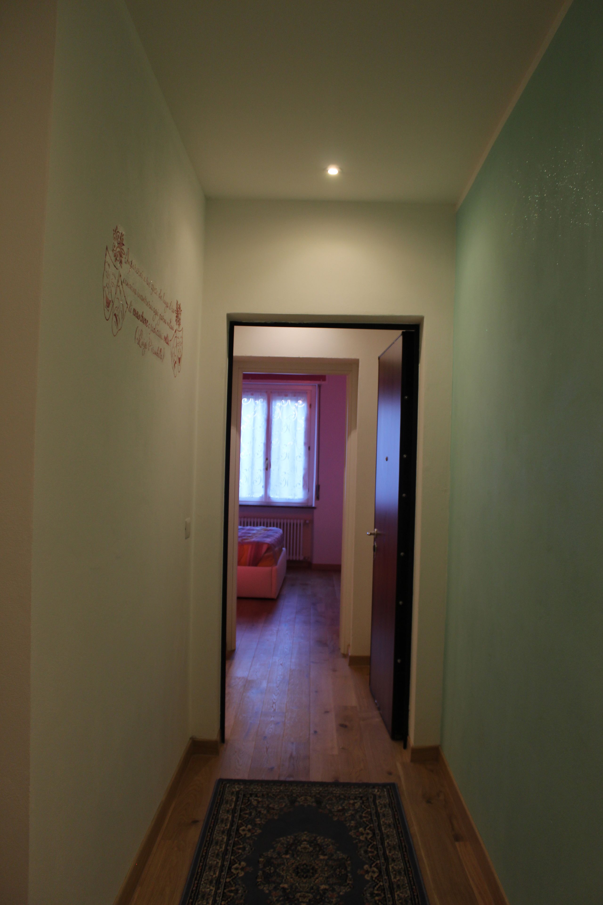 Un pasillo que conduce a una habitación con ventana y radiador.