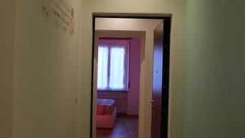 Un pasillo que conduce a una habitación con ventana y radiador.