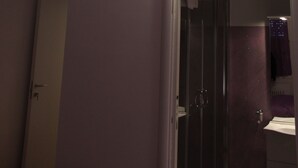 A room with a ceiling light fixture, a door leading to another room, and a wall-mounted light. - Affittacamere Pavia (Pavia)