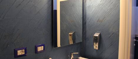 A bathroom with a white sink, a mirror, and two purple electrical outlets on the wall.