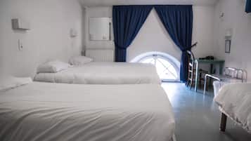 Ein Hotelzimmer mit zwei Betten, einem Schreibtisch, einem Stuhl und einem Fenster mit blauen Vorhängen.