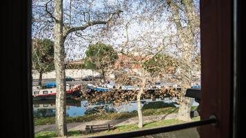 Vista de un río con barcos amarrados, árboles y un banco a lo largo de la orilla.