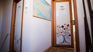 A hallway with a wooden door labeled "Room" and a map on the wall. - Il Paesino (Licodia Eubea)