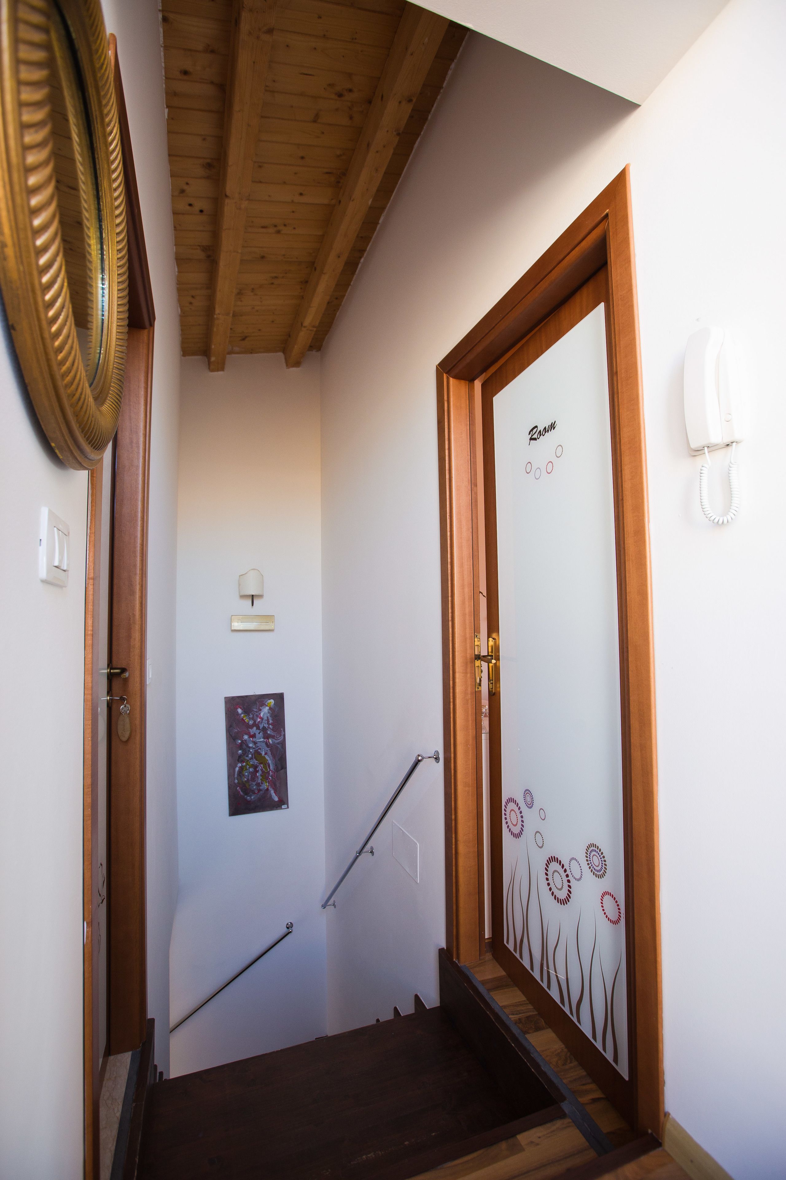 Eine Treppe mit Holzboden, die zu einem Raum führt, dessen Tür mit „Zimmer“ beschriftet ist.