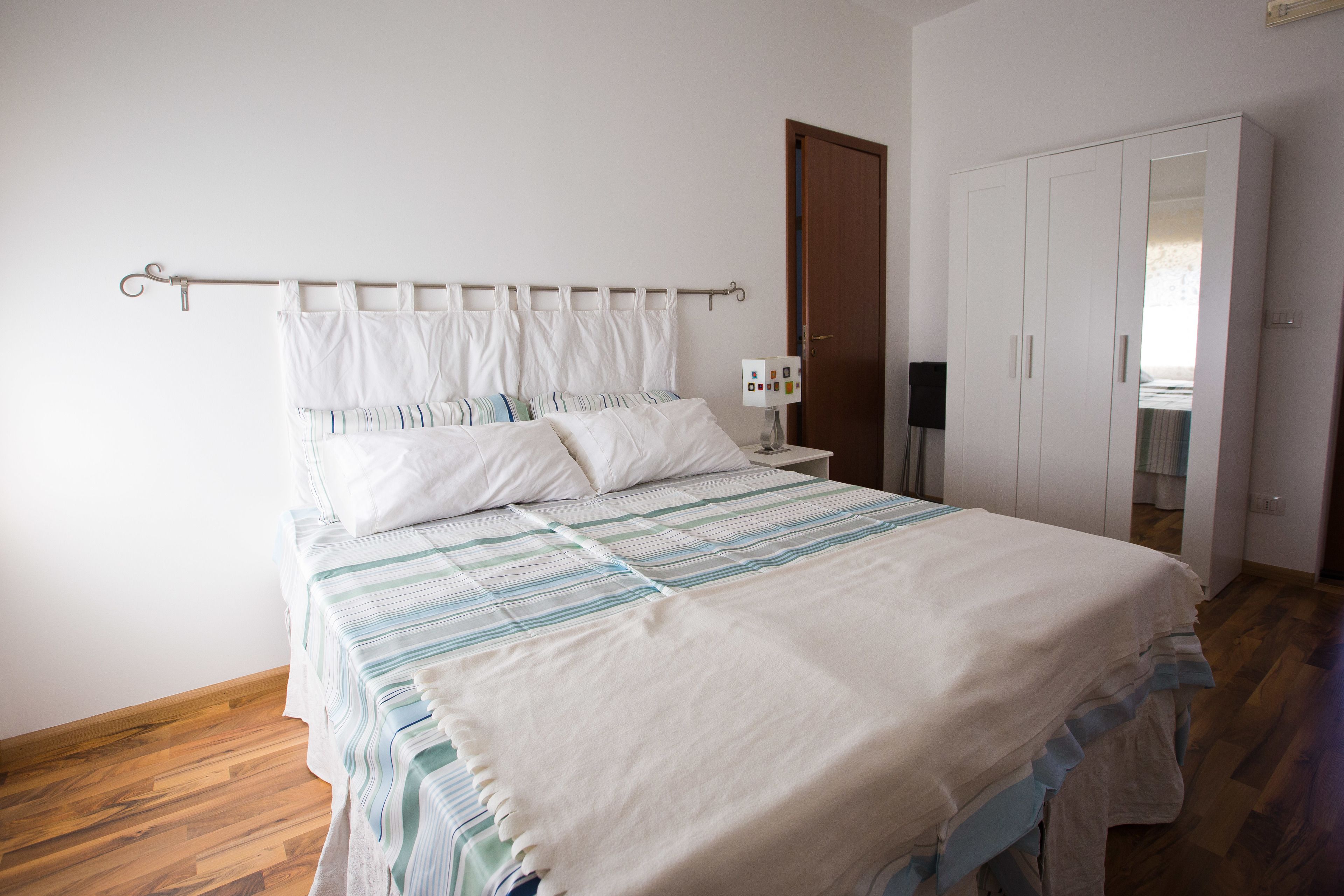 Une chambre à coucher avec un lit, une table de chevet, une armoire et une porte.