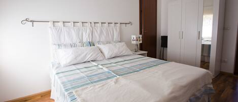Une chambre à coucher avec un lit, une table de chevet, une armoire et une porte.