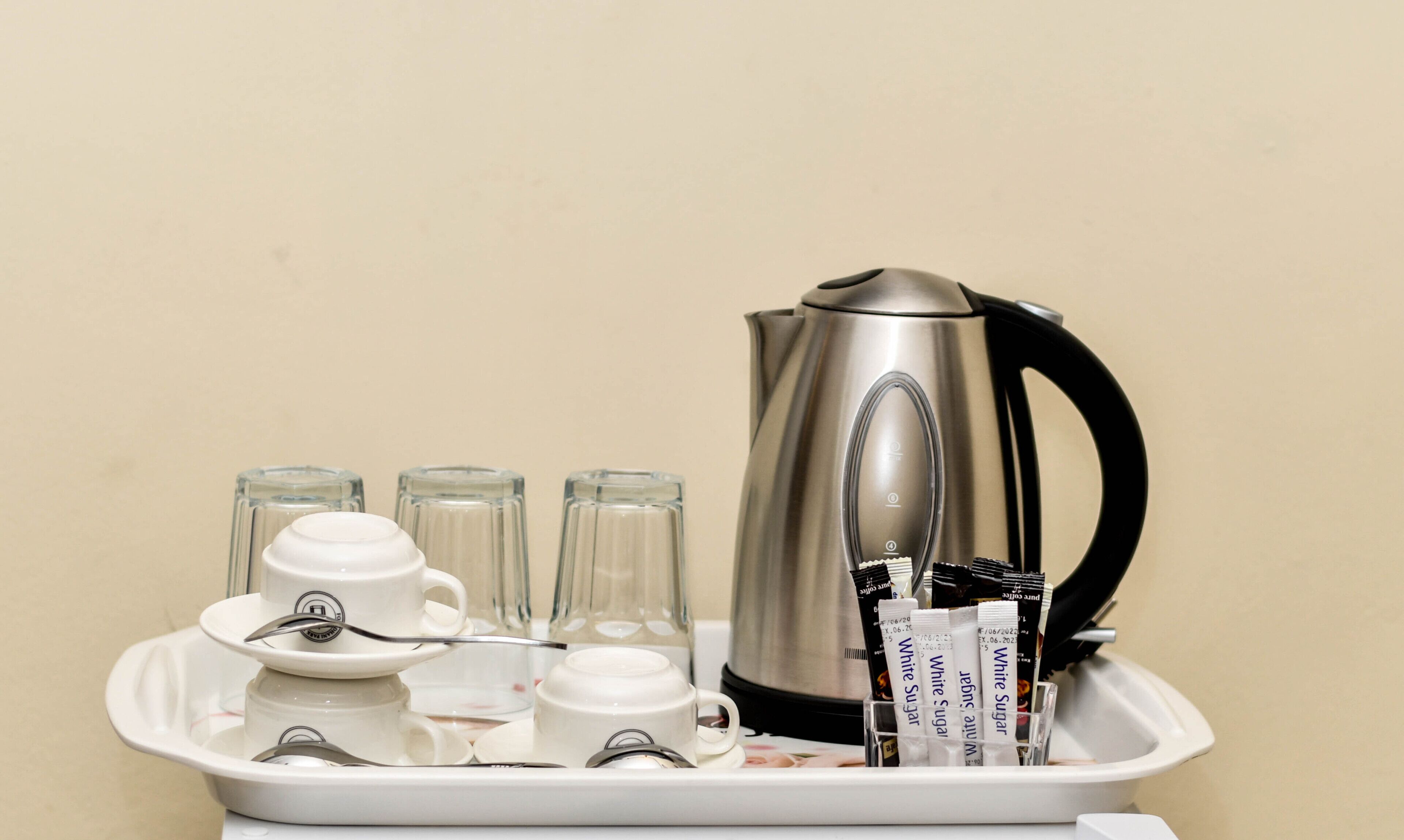 Un plateau avec une machine à café, des tasses et des sachets de sucre.