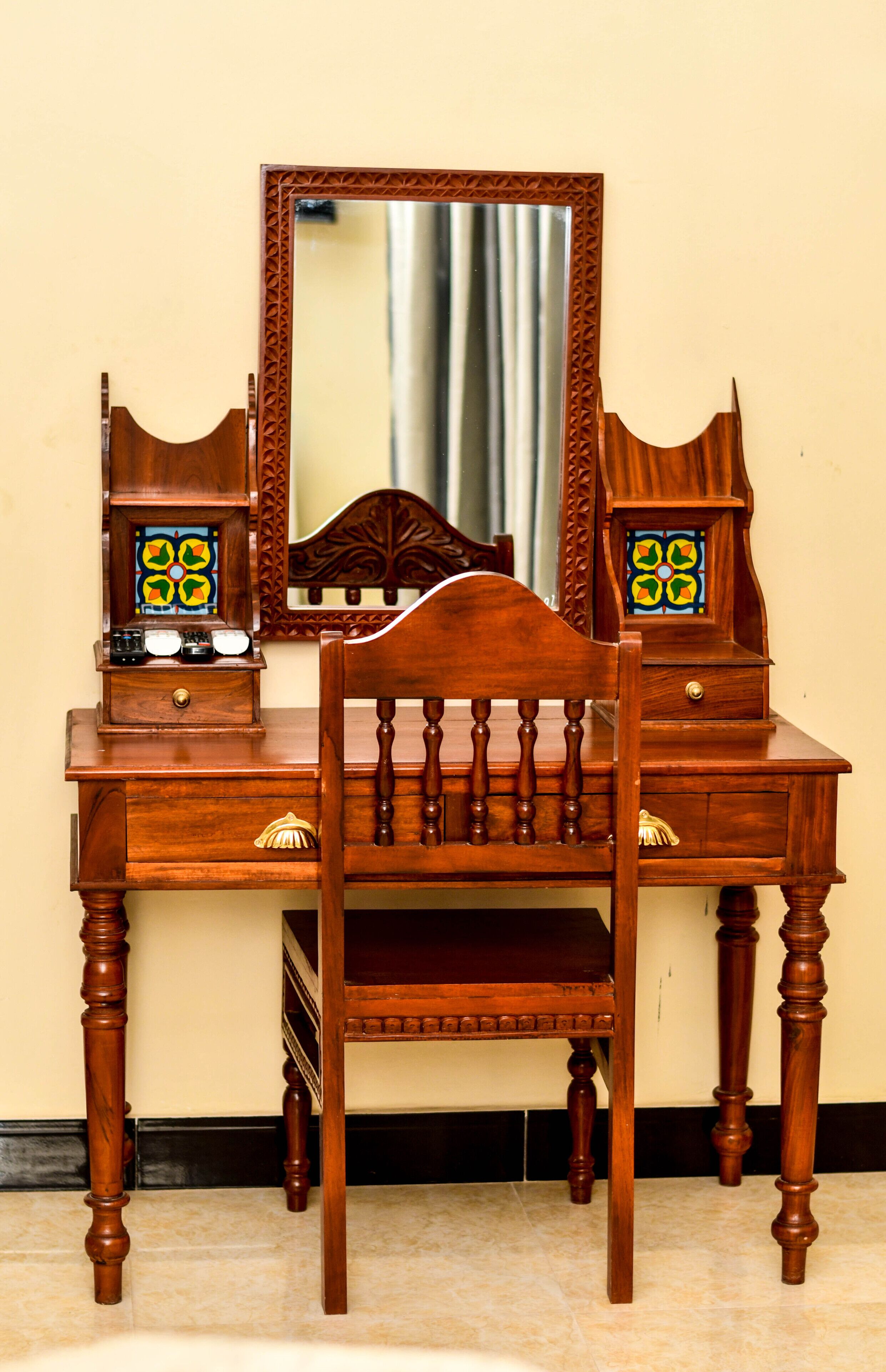 A wooden dresser with a mirror, drawers, and two decorative glass panels.