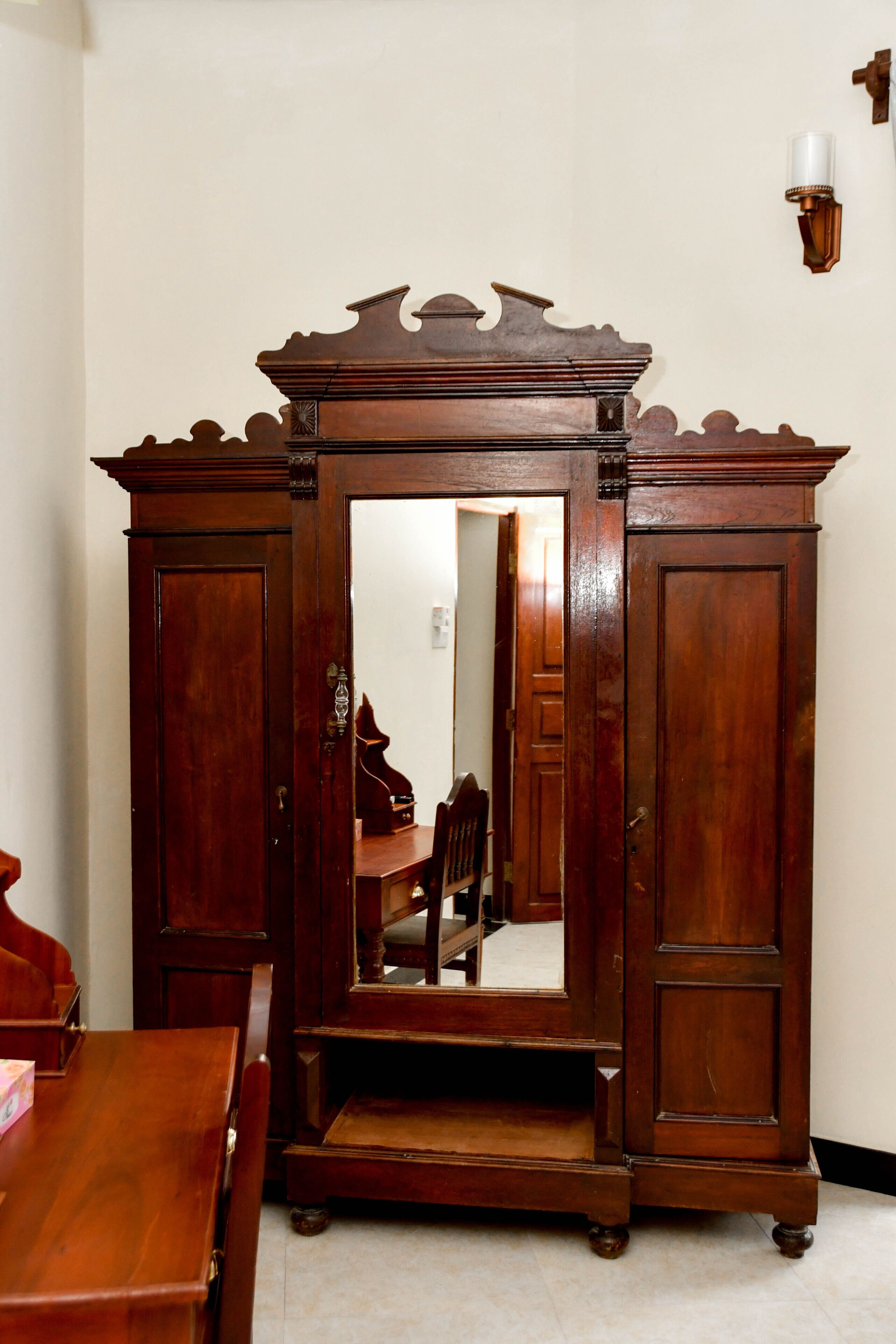 A wooden armoire with a mirror, a dining table, and chairs.
