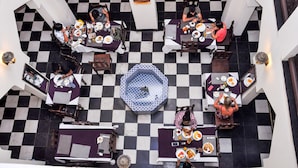 A dining area with checkered flooring and tables arranged in a central octagonal pattern. - Forodhani Park Hotel (Zanzibar Town)