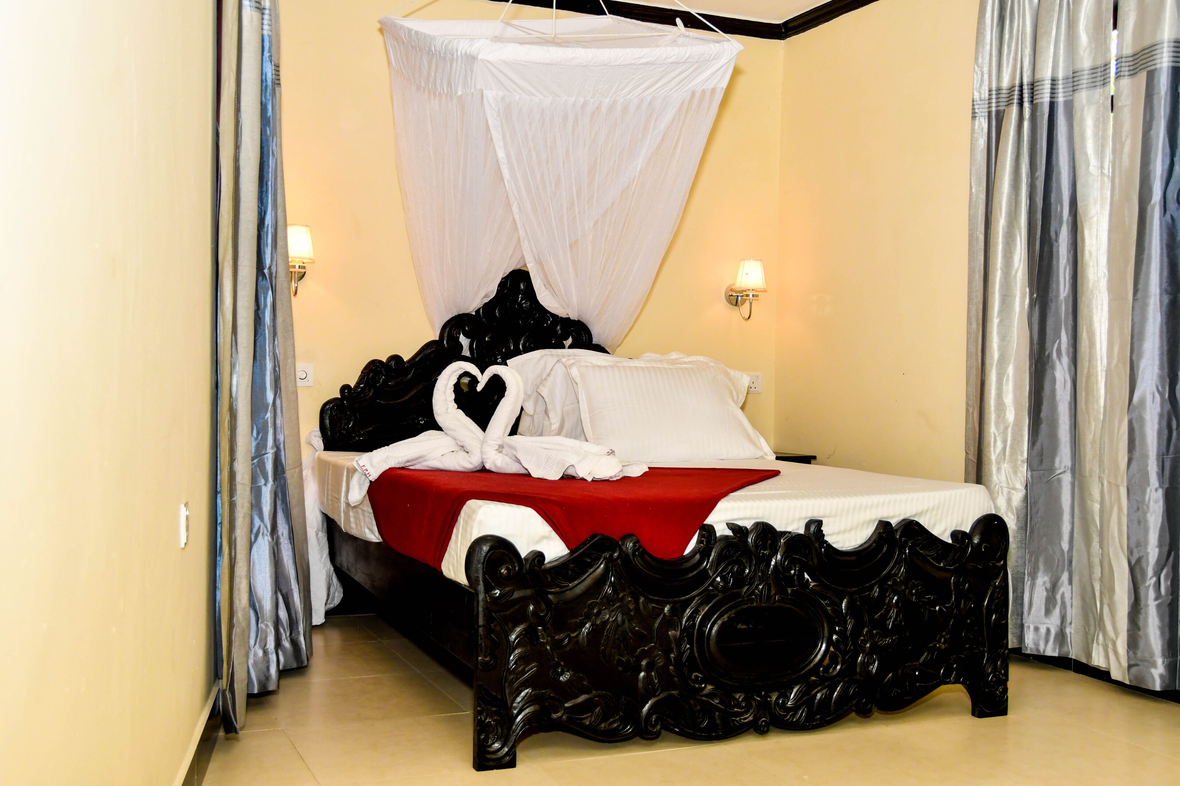 A bed with a canopy, a red bedspread, and white pillows.