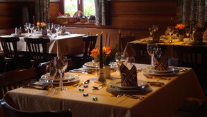 Un espace repas avec des tables mises pour le dîner, agrémenté de bougies, d’assiettes et de couverts.