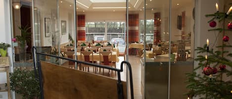 A modern hotel lobby with a high ceiling, a glass partition, and a Christmas tree with ornaments.