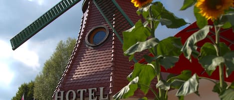 Un hotel con un molino, escalones que conducen a la entrada y una flor en primer plano.