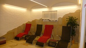 Un espace détente avec quatre fauteuils inclinables, chacun muni d’une serviette rouge, et une plante dans un coin.