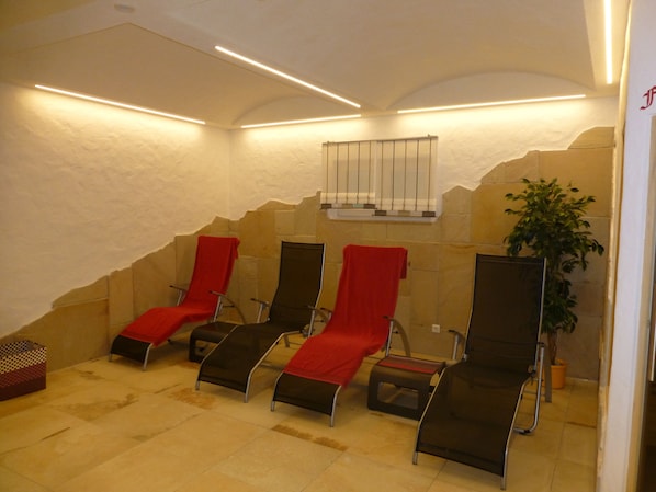 A spa area with four reclining chairs, each with a red towel, and a plant in the corner. - Hotel Gasthof zur Windmühle (Ansbach)