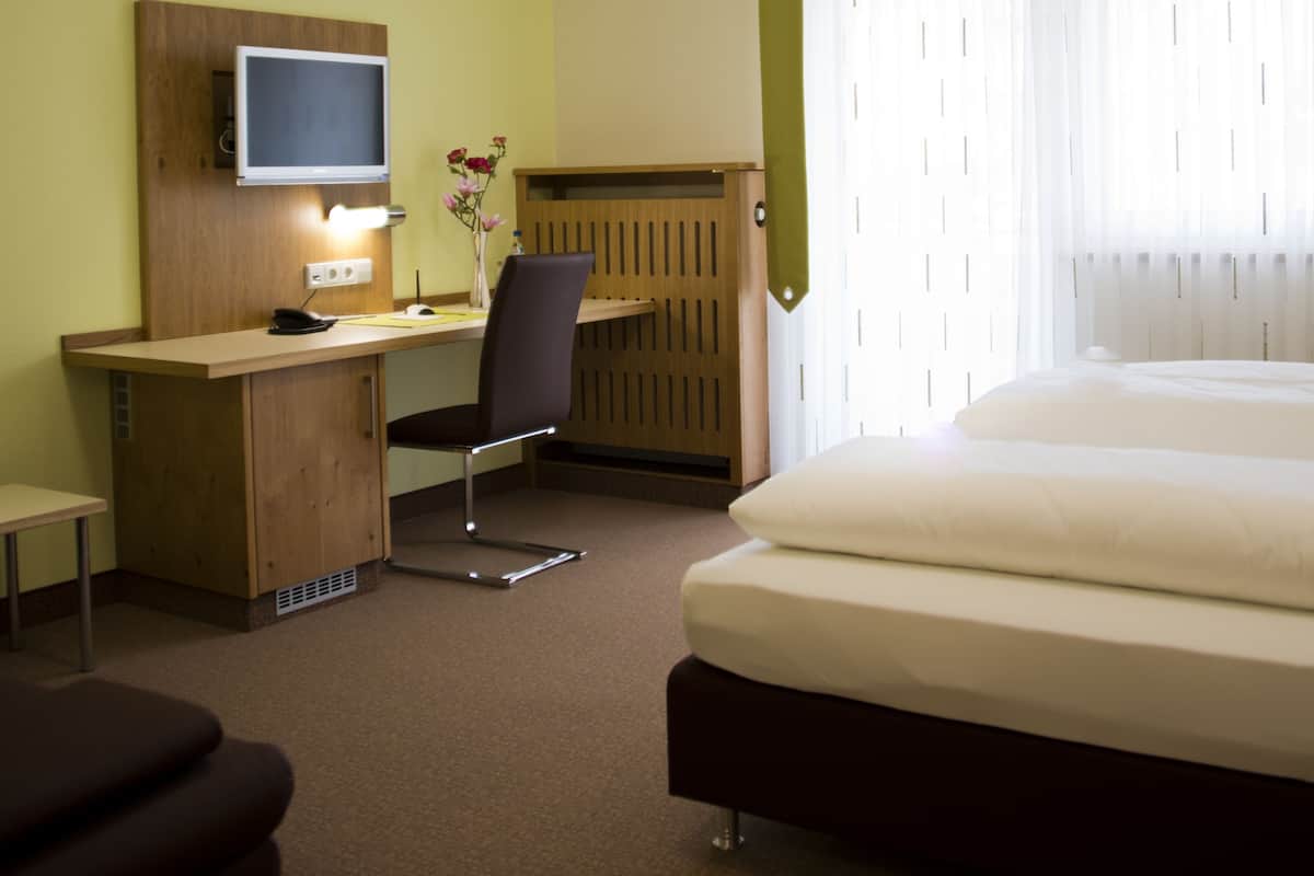 Une chambre d’hôtel comprenant un lit, un bureau avec une chaise, une télévision et une petite table.