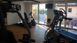 Une salle de sport équipée de matériel d’exercice, d’un tapis de course et d’une chaise.