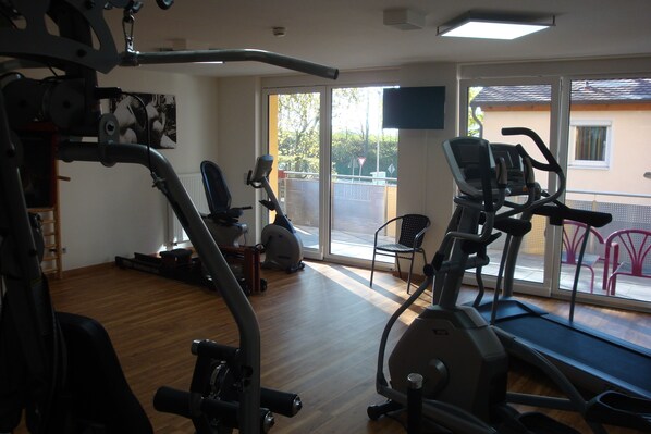 Een sportschool met trainingsapparatuur, een loopband en een stoel.