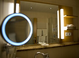 Un baño con espejo, lavamanos, toallero y zona de ducha.