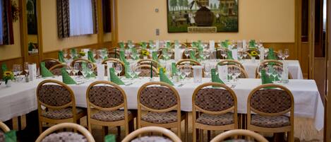 A banquet hall with multiple round tables set for dining, each with green tablecloths and white centerpieces.