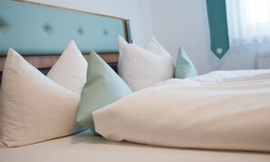 A bed with white and light green pillows and a light blue headboard.