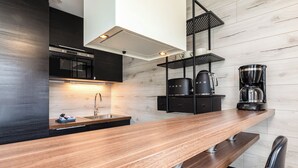 A modern kitchen with a wooden countertop, black cabinets, and a coffee maker. - Åre Travel - Center (Are)