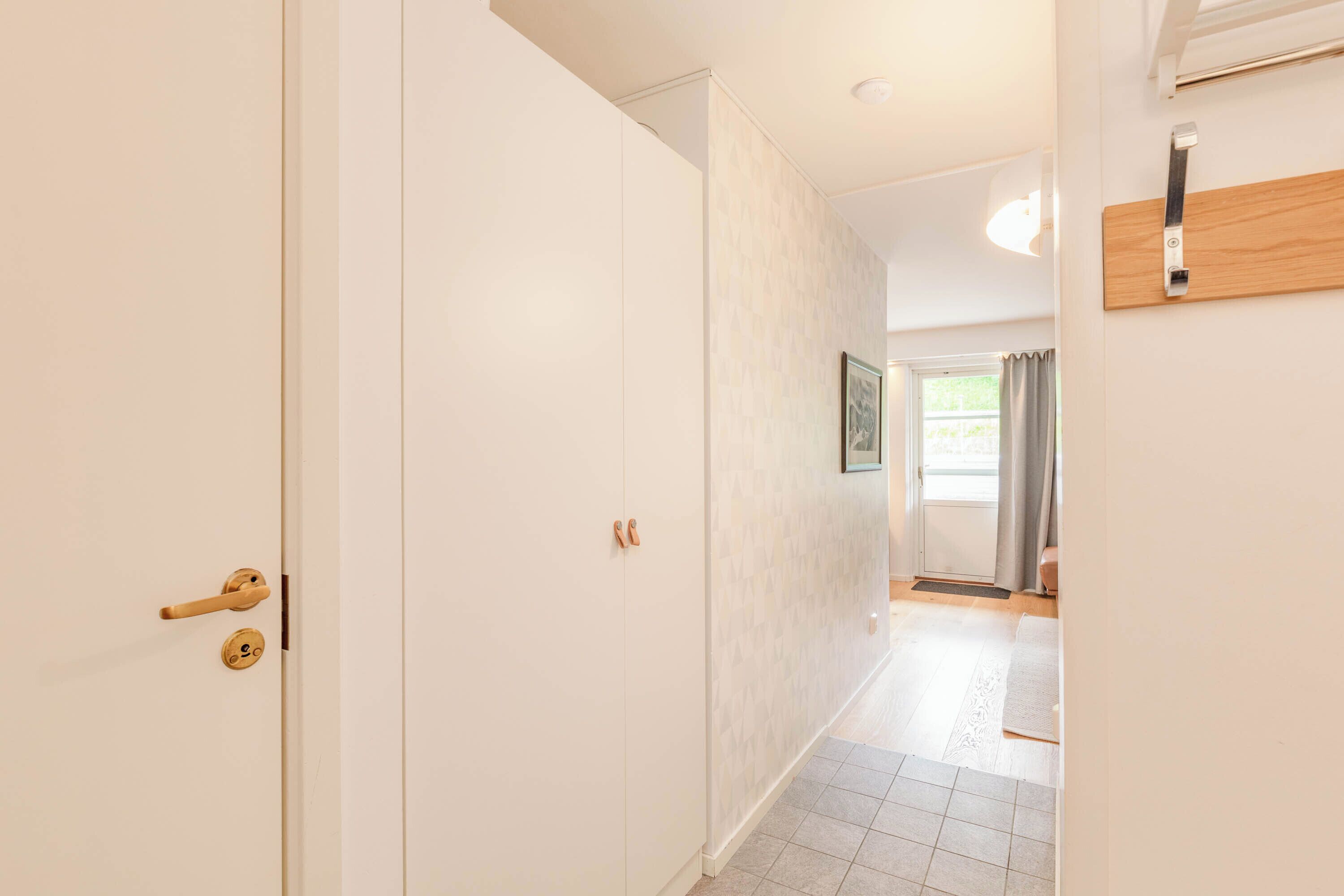 A hallway with a white door, a wooden door frame, and a light switch on the wall.