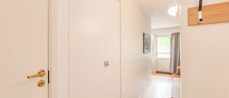A hallway with a white door, a wooden door frame, and a light switch on the wall.