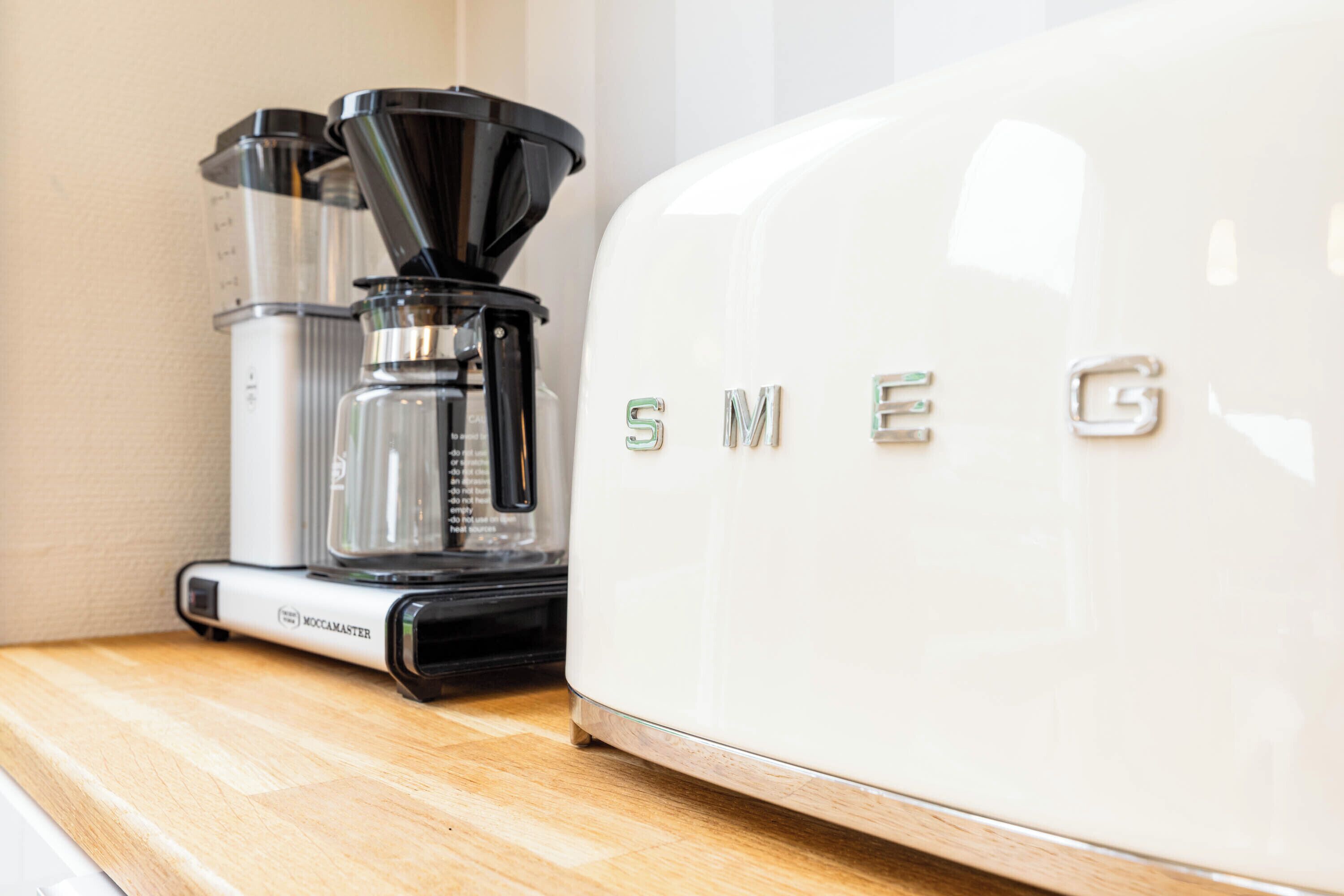 Una cafetera y un electrodoméstico blanco con el nombre de marca 'SMEG'.